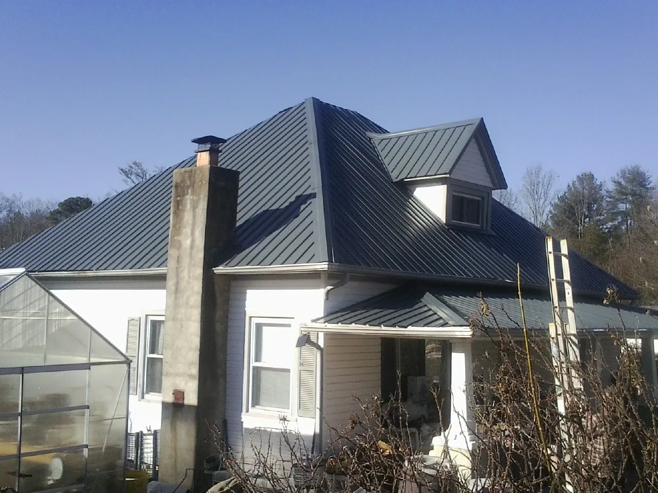 Dark blue standing seam metal roof on a white farmhouse with dormer — Slate & Tile Roof Repair by Roofing Brothers in Rhinecliff