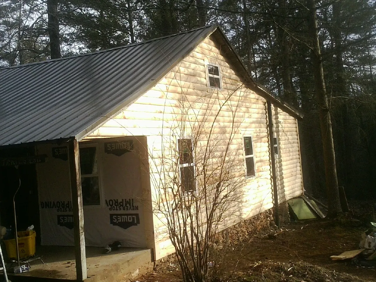 Log siding gable end under a dark metal roof edge in Rhinecliff