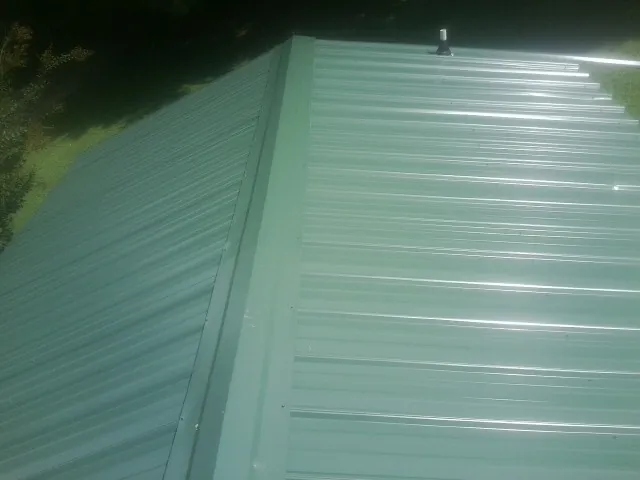 New green metal panels meeting at the ridge of a roof — Flat Roof Repair work by our crew in Rhinecliff