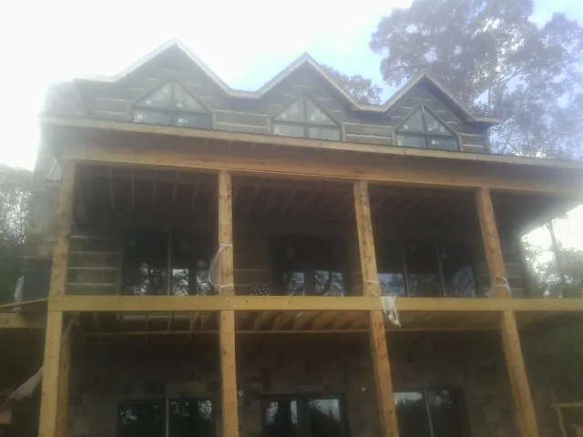 Dormers and porch framing on a large log home under construction — Roof Coating work by our crew in Rhinecliff