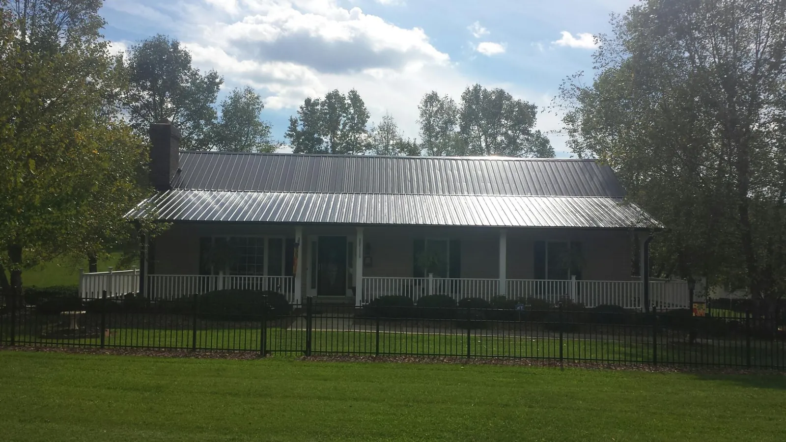 Gray metal roof on a brick ranch with a full width front porch — Gutter Guard Installation work by our crew in Rhinecliff