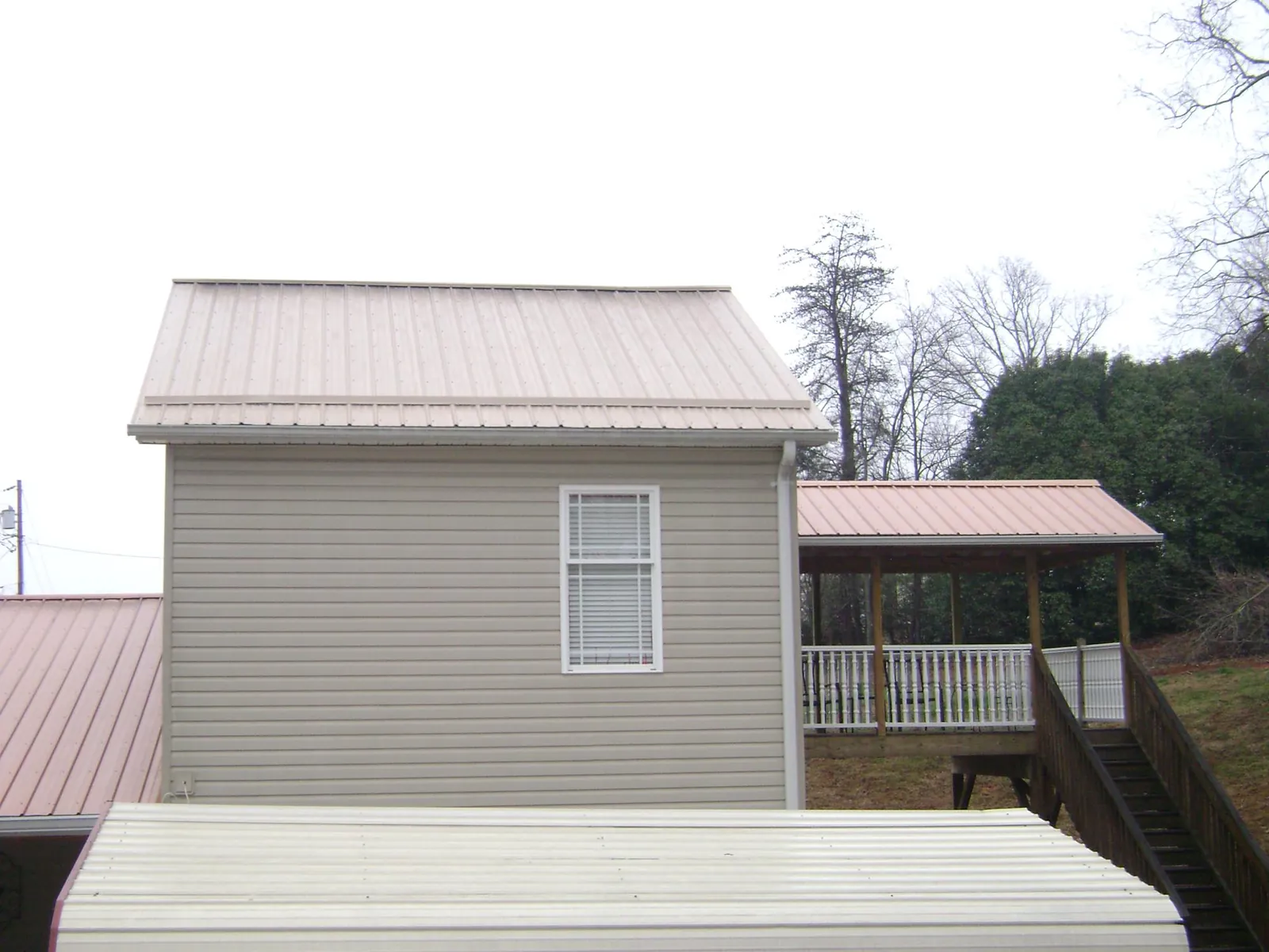 Tan metal roofs on a two story addition and attached porch, from a Roof Replacement job in Rhinecliff